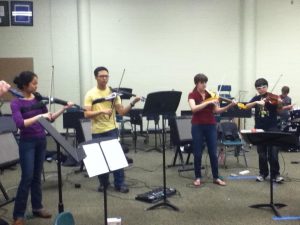 Karen Oh, 12, Michael Choi, 11, Kathryn Diaz, 12, and Luis Del Moral Lopez, 9, rehearsing “Crazy Train” by Ozzy Osbourne. They will be playing this for the Variety Show Friday. Their act is unique because they are on electric instruments, and the song is played strictly from memory. Photo by Emily Tyler.