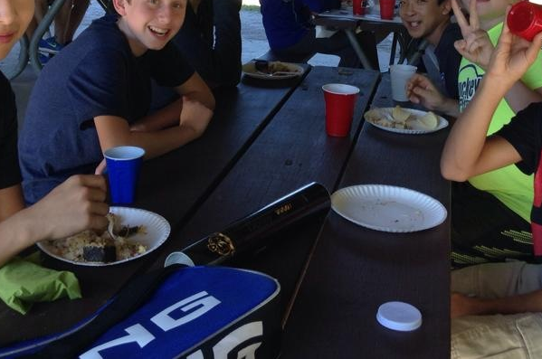 Students enjoy ethnic Chinese food at the picnic. Music plays in the background.