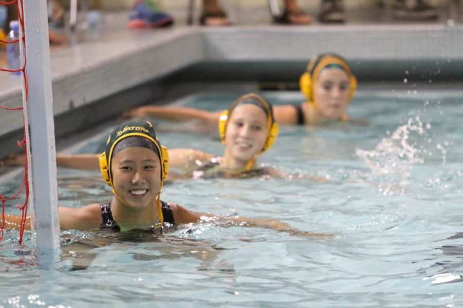 Junior Jessica Wei lines up with her teammates along the wall for the start of the game swim off. The players smile because it is their first game in the home pool after the draining and refilling process. The game was against Princeton and all Sycamore teams won that day.