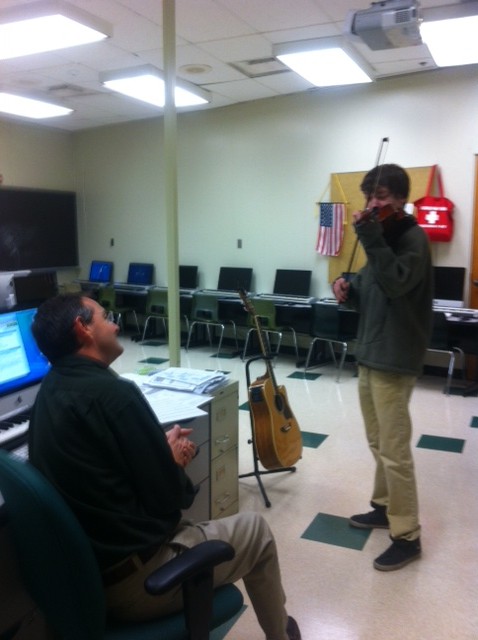 Sophomore Ethan Haight performs the test for Mr. Swift in the music technology room. Students play along with a recording of the rest of the orchestra’s parts. Mr. Swift often cuts students off because the testing would take too long if everyone did the entire piece. Photo by Jenna Bao.