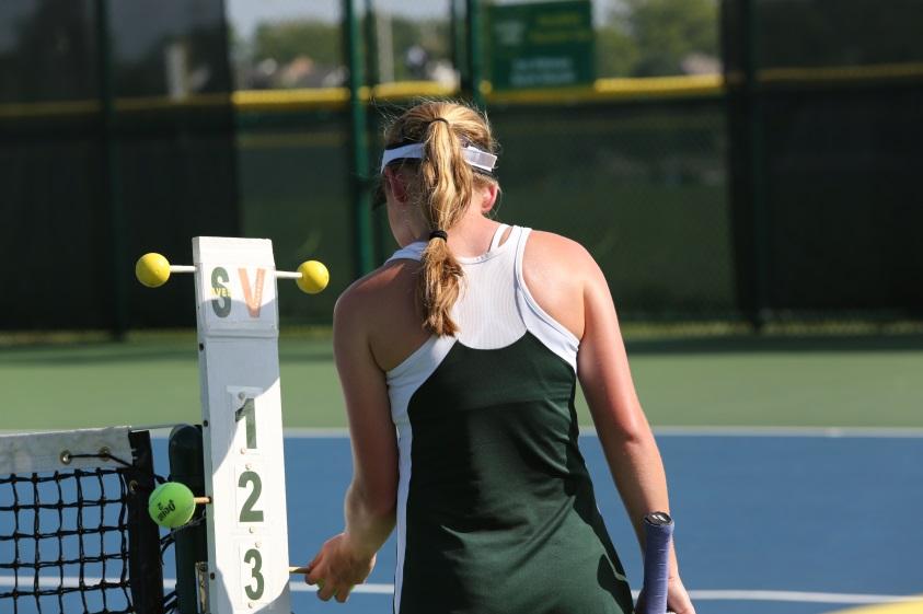 Changing the score for a singles match, junior Alexandra Abele , moves the tennis ball to number three on the score card, signaling the end of the 5th game.  This is a task that either team could take responsibility for after every odd numbered game. 