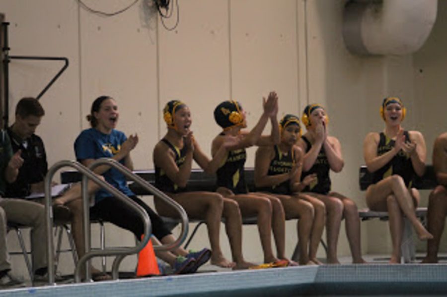 After Kast wins the swim off her teammates are seen cheering on the side lines. The team sets up for offense and works the ball around in order to score. They work to get open water so that they can keep the ball moving and they can create an opening in the goal. 