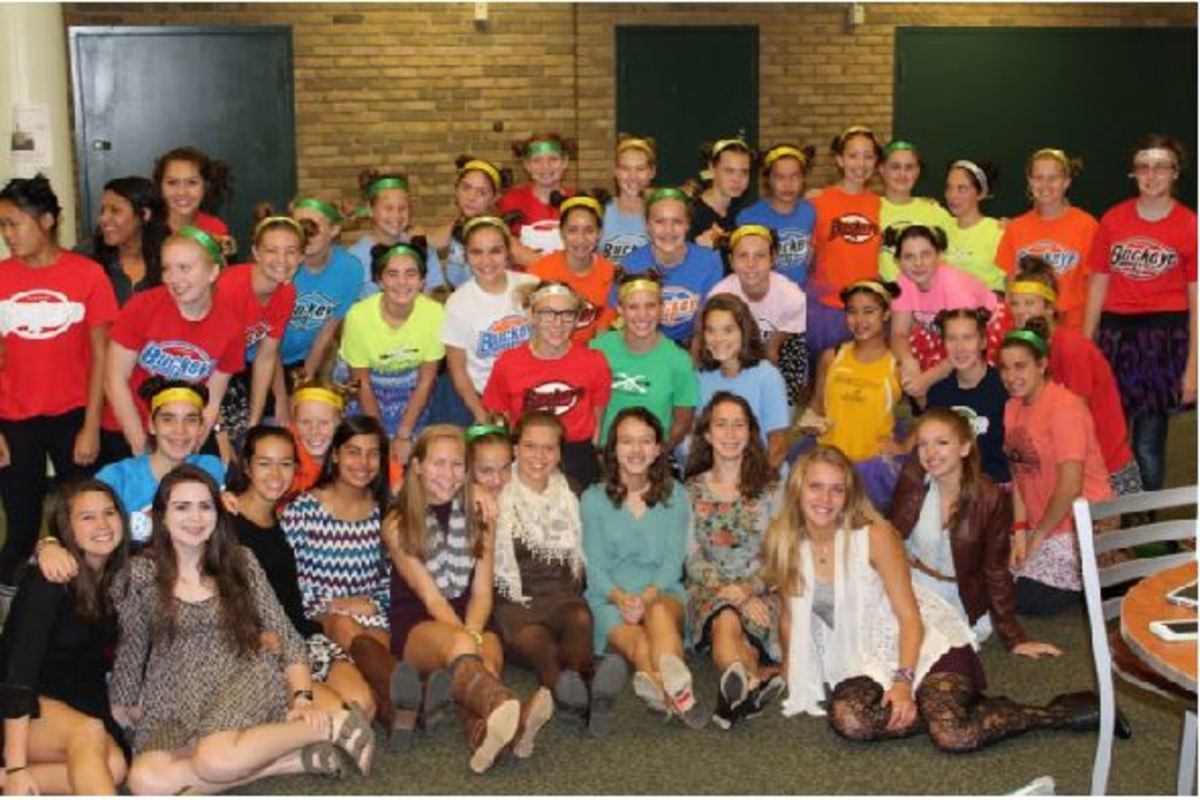 The cross country team and their seniors pose for a picture after a Friday morning practice. They are all wearing buckeye running shirt, skirts, jeans, long socks and sandals for their senior night. They wore this outfit throughout the entire school day.