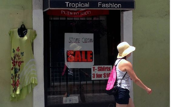 A woman walks past a shop in Puerto Rico where it is not unusual to see closed shops. The closing shop displays the cruelty of the current financial crisis. The financial crisis is causing many to leave Puerto Rico.