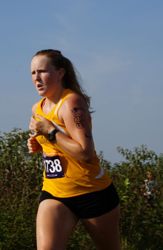 enior Allison Kossen as she races through the VOA field. She sports a homemade cross country tattoo. Creating these tattoos before a race is a cross country tradition. 
