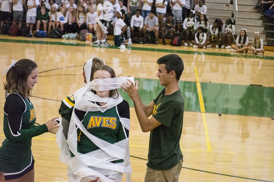 “RAPT” ATTENTION. Seniors Matthew Isakson and Constance Kavensky hurry to wrap seniors Julia McDowell and Jeremy Pletz. After the homecoming court from each grade was introduced, they competed together. One couple from each grade wrapped the other pair with toilet paper like mummies. The juniors were picked as the winners by the volume of their cheering.