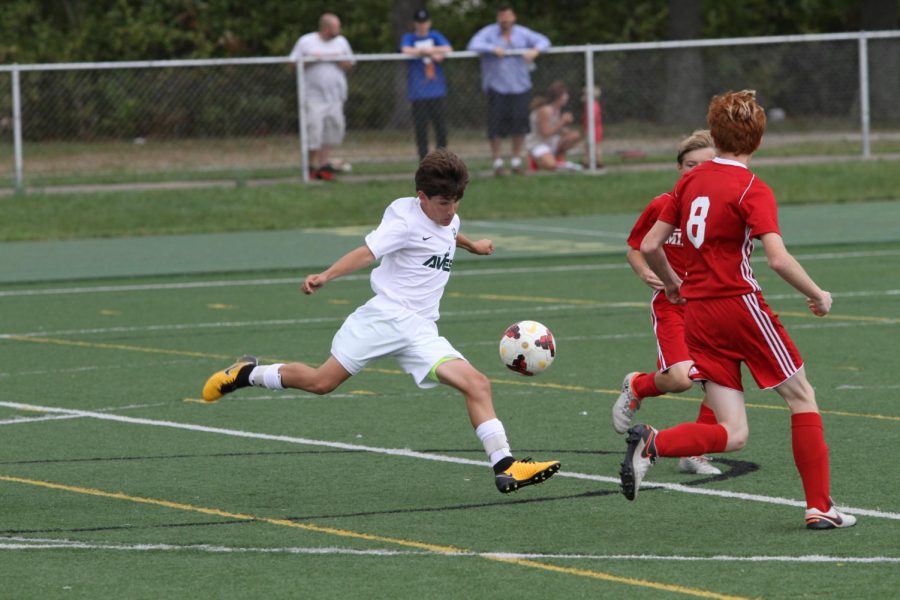 KICKIN’ IT. Freshman Benjamin Margolis steals the ball away from the Milford team. “I have really enjoyed being on the soccer team. It was nice knowing that the pre-season training with the upperclassmen allowed me to have friendly faces in the hallway,” Margolis said. 