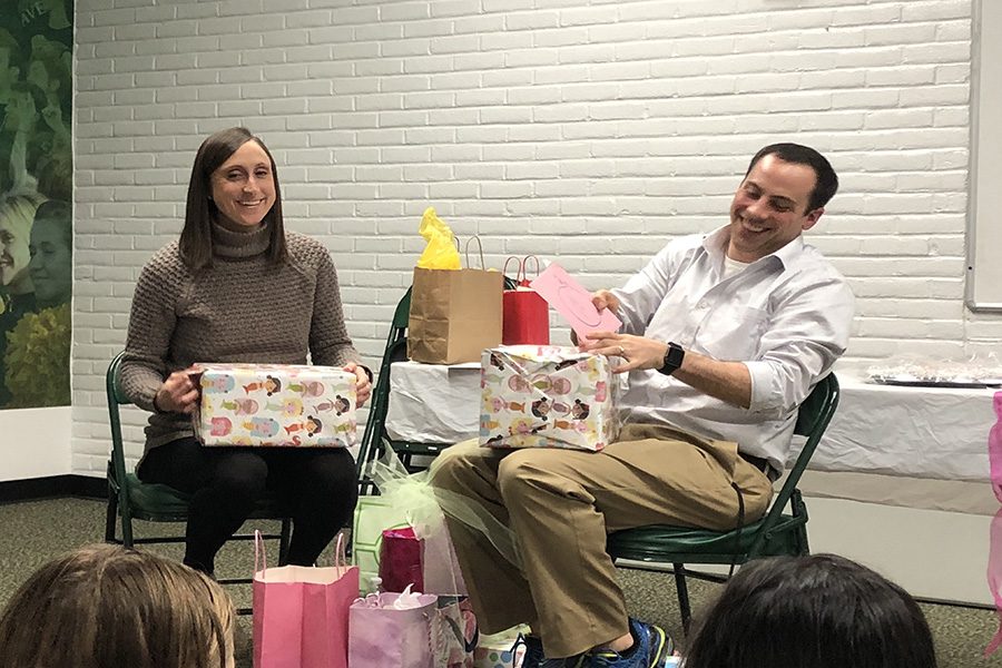 IT’S A GIRL. Assistant coach Stephen Langdon and his wife Carly open up presents gifted from the Varsity swimmers. The Langdons received a variety of gifts ranging from onesies to diapers. The party took place at 4:30 p.m. directly after swim practice in the team room. 