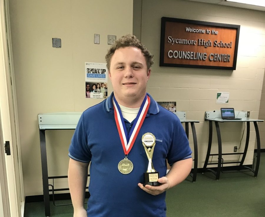 DOMINATE. Senior Christopher Banzhaf wears his medal from achieving sixth in state and holds the trophy from first at regionals. Banzhaf focused on sound editing and some video editing. “We all chipped in and did it together,” Banzhaf said. 