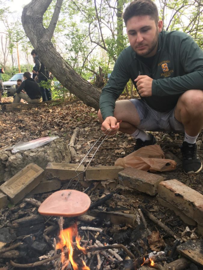 BLAZE. Senior, Trevor Size cooks a ham steak over self-made campfire as a part of the camping unit for the outdoor recreation gym class. Students may choose to make any meal they want over the fire if they supply their own materials and clean up themselves.“It was a new, interesting experience that I will probably not try again. Although I’m not the outdoorsy type I gained a new appreciation for nature,” Xadi Ndiaye, 11.

