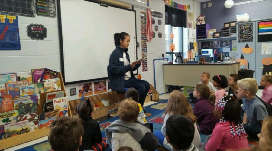 GIVING BACK. Seniors spent the day on Tues., Oct. 16 helping out in various local places. Pictured is senior Hannah Lee reading to a class of first graders at Blue Ash Elementary School. Popular locations were younger grade schools and community organizations such as Matthew 25 Ministries. It is a rewarding experience and lasting memory for both seniors and community members.