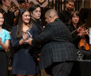 Julia Lancman, 10, receives an award at an orchestra concert.