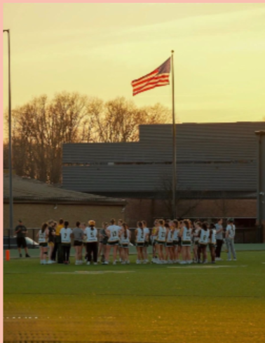 Members of the girls' lacrosse team huddle during a lacrosse practice.